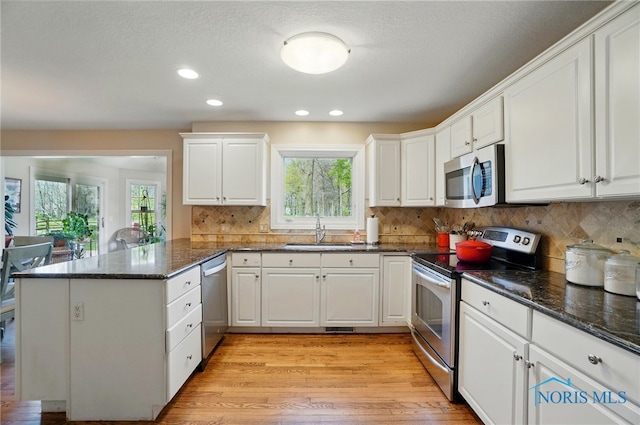 8420 Willow Glen Ct, Holland, OH 43528 - kitchen featuring stainless steel appliances, a sink, a peninsula, light wood-style floors, and white cabinets