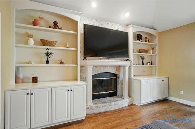 8420 Willow Glen Ct, Holland, OH 43528 - unfurnished living room with light wood-type flooring, a fireplace, built in features, vaulted ceiling, and baseboards