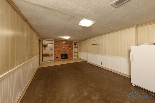 633 Hillcrest Ave, Findlay, OH 45840 - finished basement with freestanding refrigerator, a brick fireplace, a textured ceiling, and wood walls