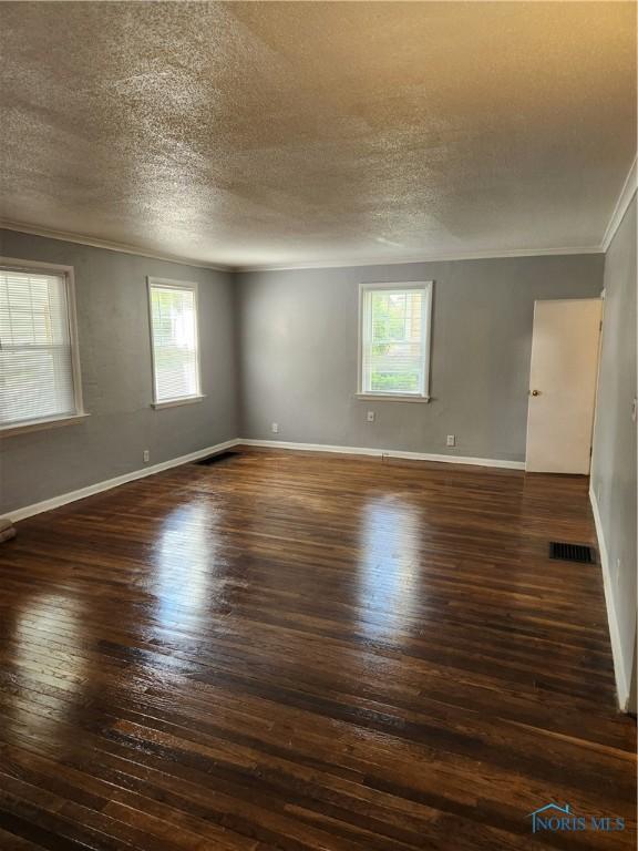 815 S Blanchard St, Findlay, OH 45840 - unfurnished room featuring dark wood-type flooring, crown molding, a textured ceiling, plenty of natural light, and baseboards