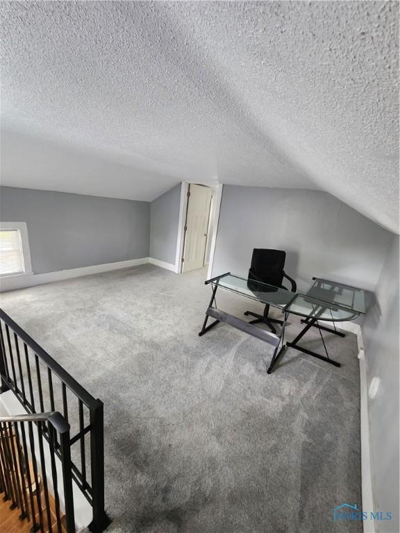815 S Blanchard St, Findlay, OH 45840 - living area featuring carpet flooring, a textured ceiling, baseboards, vaulted ceiling, and an upstairs landing
