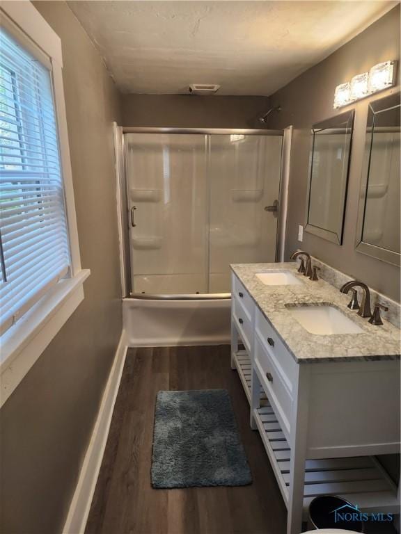 815 S Blanchard St, Findlay, OH 45840 - bathroom featuring wood finished floors, combined bath / shower with glass door, double vanity, and baseboards