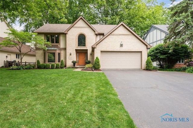 2426 Gibley Park Rd, Toledo, OH 43617 - tudor house with an attached garage, asphalt driveway, a front lawn, and brick siding