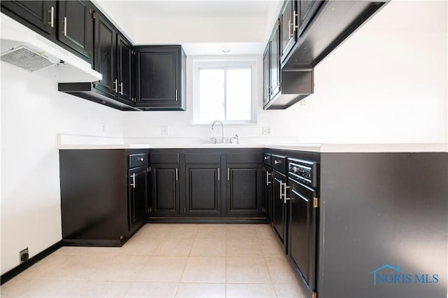 1621 Acorn Dr, Toledo, OH 43615 - kitchen with under cabinet range hood, light countertops, light tile patterned floors, and dark cabinets
