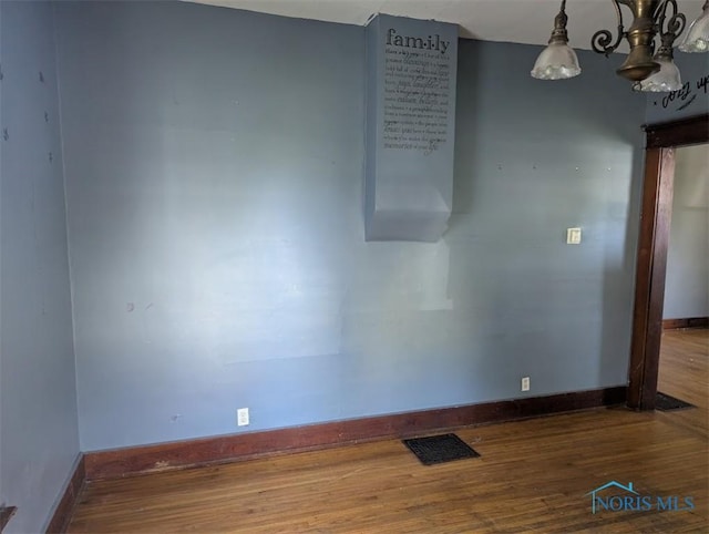1022 Dodd St, Napoleon, OH 43545 - empty room with wood finished floors, baseboards, and a chandelier