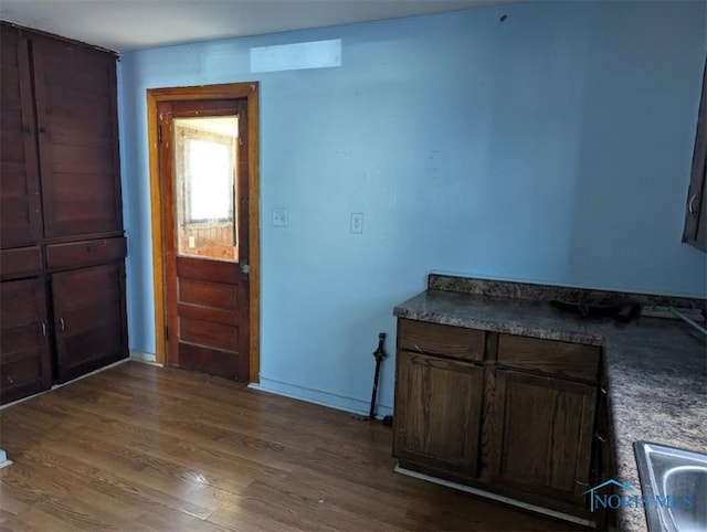 1022 Dodd St, Napoleon, OH 43545 - kitchen with wood finished floors, baseboards, a sink, and dark brown cabinetry