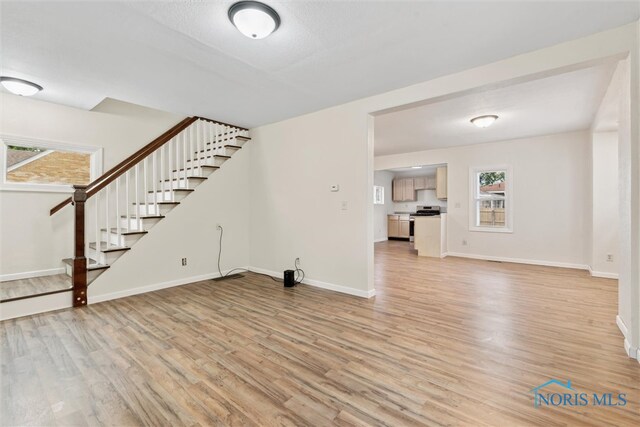 3409 Kirby Pl, Toledo, OH 43608 - unfurnished living room featuring stairs, light wood finished floors, and baseboards