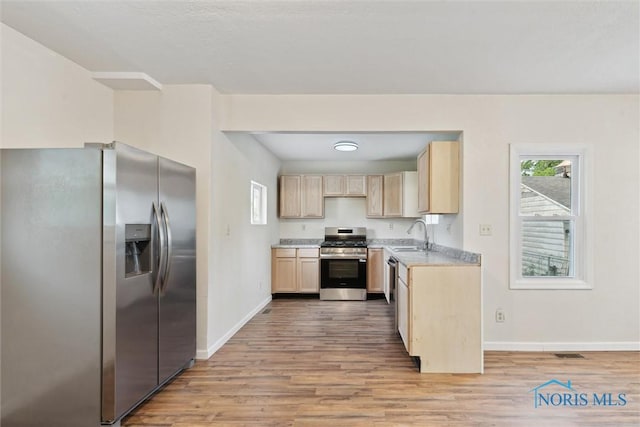 3409 Kirby Pl, Toledo, OH 43608 - kitchen with stainless steel appliances, light brown cabinetry, light wood-style flooring, baseboards, and light countertops