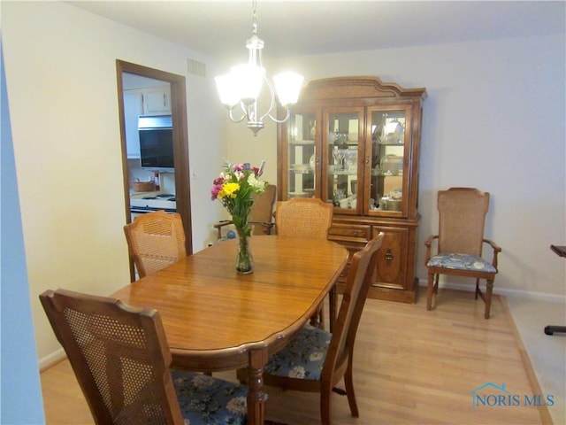 4343 W Bancroft St Unit 2D, Toledo, OH 43615 - dining room featuring a chandelier, light wood-type flooring, and baseboards