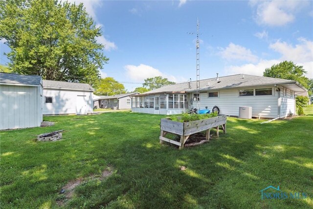 955 Westmont Ave, Napoleon, OH 43545 - rear view of property featuring a sunroom, a lawn, and an outdoor structure