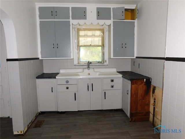 1839 Talbot St, Toledo, OH 43613 - kitchen featuring tile walls, arched walkways, dark wood-style flooring, and a sink