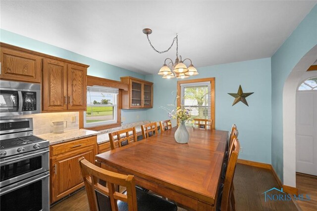 15819 County Road D, Wauseon, OH 43567 - dining room with arched walkways, dark wood finished floors, a chandelier, and baseboards