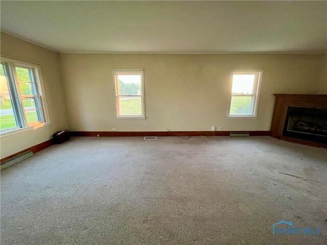 11157 State Route 500, Paulding, OH 45879 - unfurnished living room with plenty of natural light, a fireplace with flush hearth, baseboards, and carpet floors