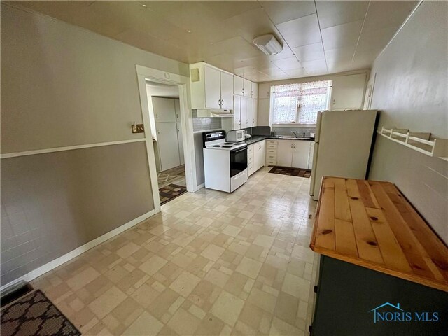 11157 State Route 500, Paulding, OH 45879 - kitchen featuring white appliances, white cabinets, under cabinet range hood, dark countertops, and baseboards