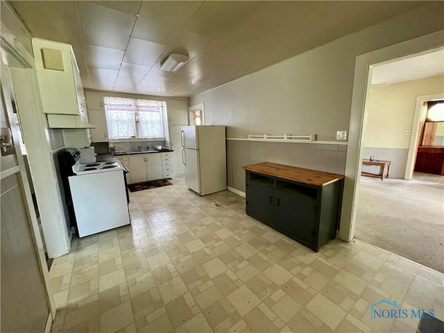 11157 State Route 500, Paulding, OH 45879 - kitchen featuring white appliances, white cabinets, under cabinet range hood, a sink, and wainscoting