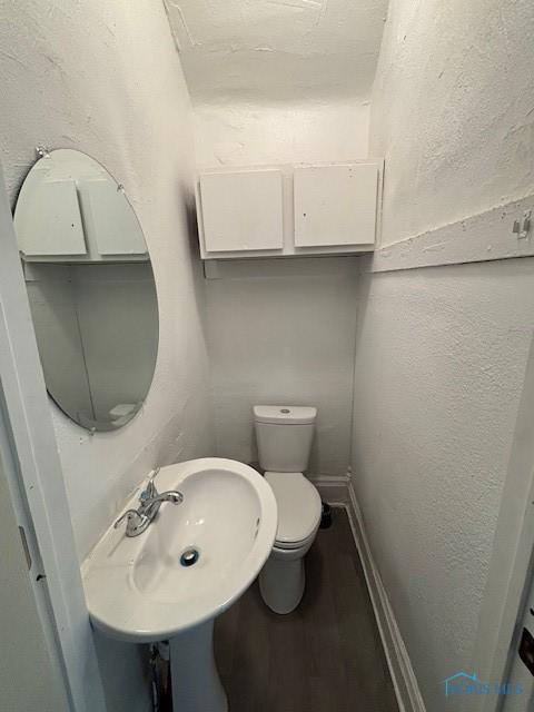 3239 Cherry St, Toledo, OH 43608 - half bath with baseboards, a sink, toilet, wood finished floors, and a textured wall