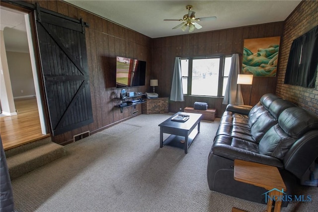 1133 Cuba St, Toledo, OH 43615 - carpeted living area featuring a barn door, ceiling fan, wooden walls, ornamental molding, and baseboards