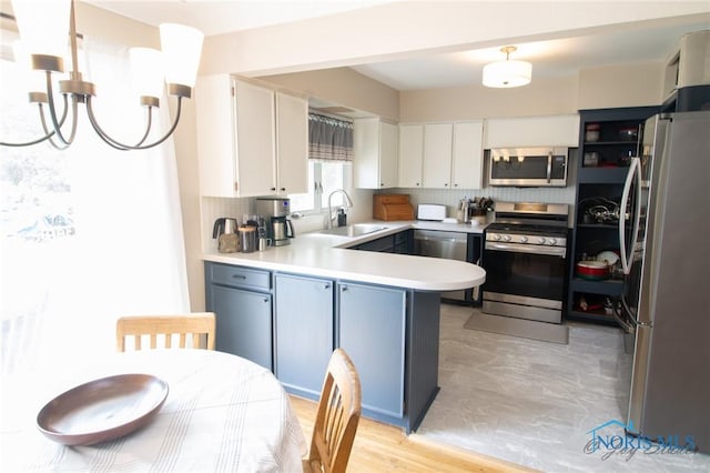1133 Cuba St, Toledo, OH 43615 - kitchen with stainless steel appliances, a sink, a peninsula, light countertops, and white cabinets