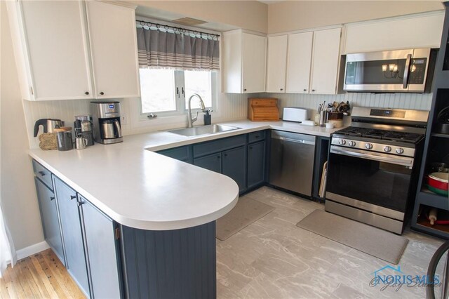 1133 Cuba St, Toledo, OH 43615 - kitchen featuring appliances with stainless steel finishes, a sink, a peninsula, light countertops, and white cabinets