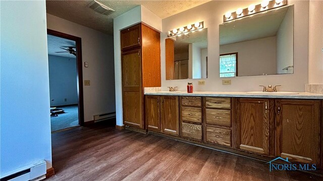 13926 Rd 154, Paulding, OH 45879 - bathroom with baseboard heating, wood finished floors, double vanity, and a textured ceiling