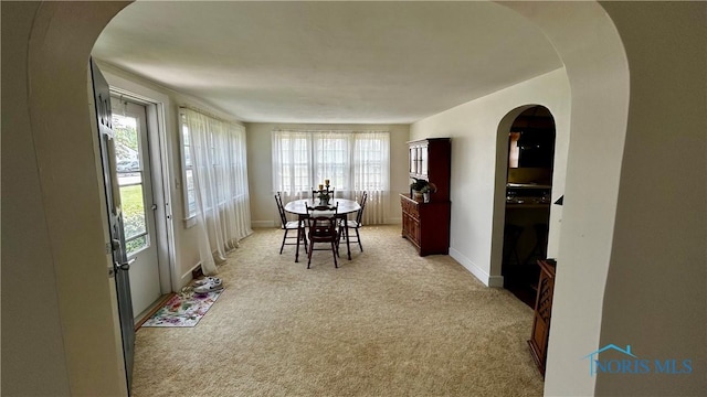 606 Lincoln Ave, Paulding, OH 45879 - dining room featuring healthy amount of natural light, light colored carpet, baseboards, and arched walkways