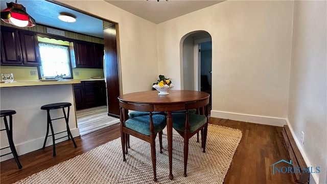 606 Lincoln Ave, Paulding, OH 45879 - dining area featuring arched walkways, dark wood finished floors, baseboards, and a baseboard radiator