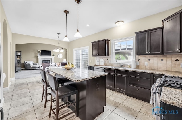 4360 Turtle Creek Dr, Perrysburg, OH 43551 - kitchen featuring a sink, gas stove, decorative backsplash, light stone counters, and a glass covered fireplace