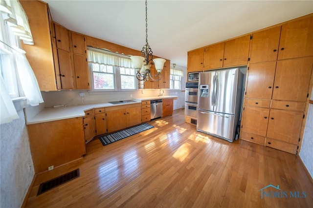 313 E Lynn St, Edgerton, OH 43517 - kitchen with stainless steel appliances, light wood-type flooring, a chandelier, light countertops, and brown cabinets