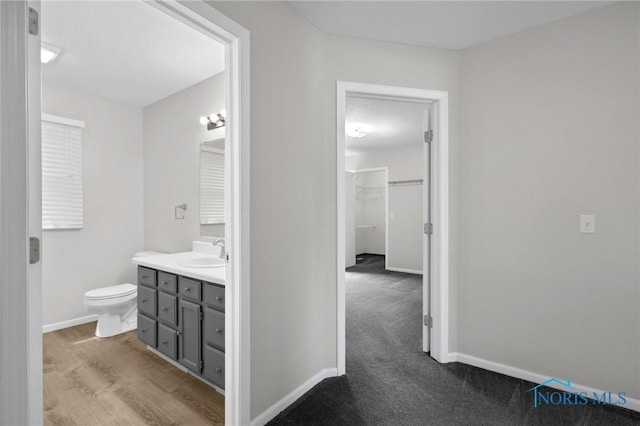 1141 Oriole Dr, Bowling Green, OH 43402 - bathroom with vanity, toilet, a walk in closet, and baseboards