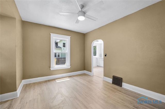 345 W Manhattan Blvd, Toledo, OH 43608 - empty room with arched walkways, ceiling fan, light wood-style floors, and baseboards