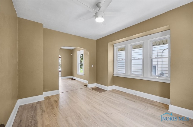 345 W Manhattan Blvd, Toledo, OH 43608 - unfurnished room with arched walkways, wood finished floors, a ceiling fan, and baseboards