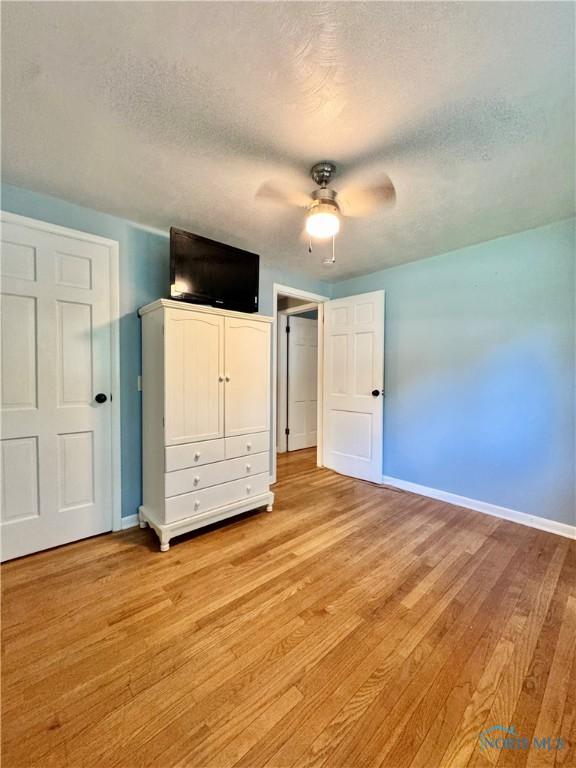 309 Koerber Dr, Defiance, OH 43512 - unfurnished bedroom featuring a textured ceiling, light wood-style floors, and ceiling fan