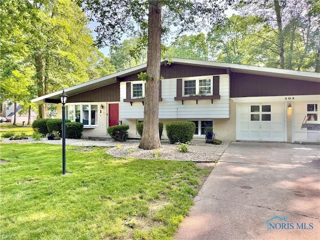 309 Koerber Dr, Defiance, OH 43512 - tri-level home featuring a front yard, a garage, concrete driveway, and brick siding