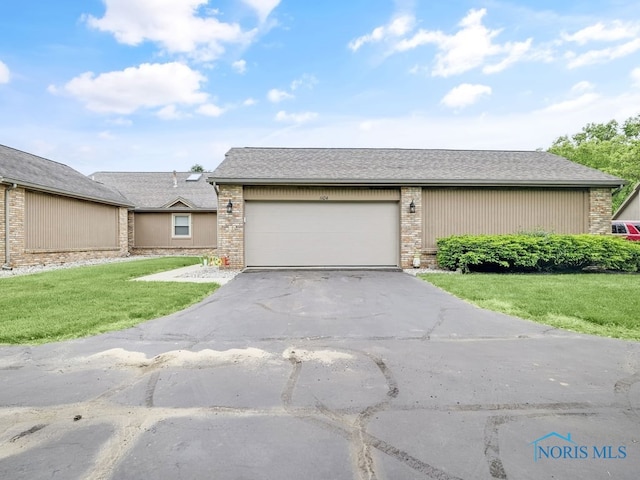 1104 Bernath Pkwy, Toledo, OH 43615 - view of front facade featuring asphalt driveway, a front yard, a garage, and brick siding