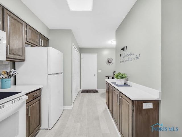 1104 Bernath Pkwy, Toledo, OH 43615 - kitchen with light countertops, light wood finished floors, white appliances, baseboards, and dark brown cabinets