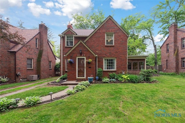3127 Drummond Rd, Toledo, OH 43606 - tudor-style house featuring a front lawn, brick siding, cooling unit, and a chimney
