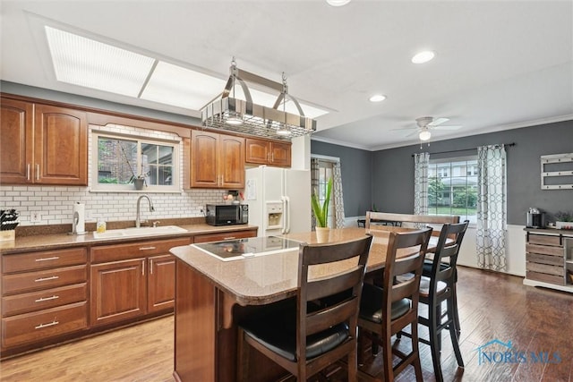 3127 Drummond Rd, Toledo, OH 43606 - kitchen with a sink, white refrigerator with ice dispenser, black microwave, crown molding, and a breakfast bar