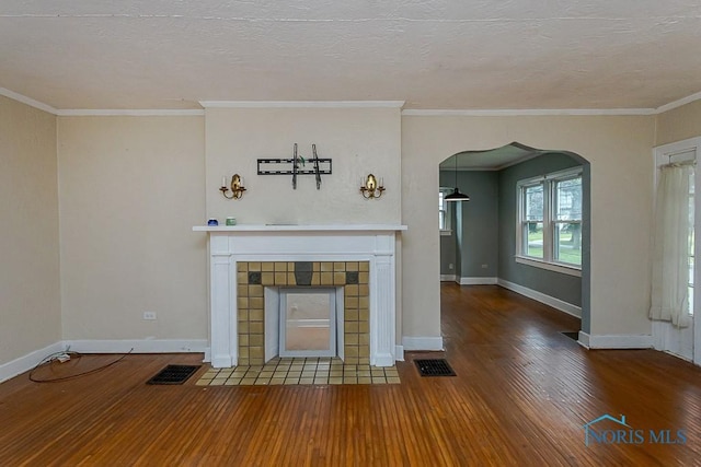 3819 Rushland Ave, Toledo, OH 43613 - unfurnished living room with a tile fireplace, wood-type flooring, arched walkways, ornamental molding, and a textured ceiling