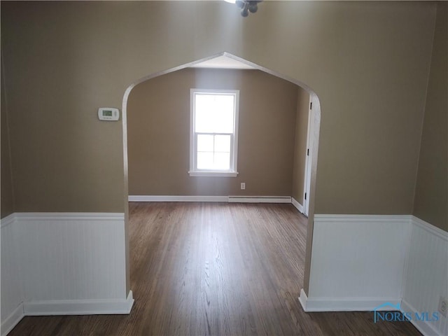 2417 Lambert Dr, Toledo, OH 43613 - spare room featuring arched walkways, wainscoting, wood finished floors, and baseboard heating