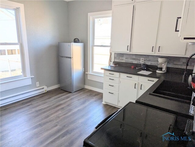 726 S Lynn St, Bryan, OH 43506 - kitchen featuring freestanding refrigerator, a baseboard heating unit, dark countertops, white cabinets, and tasteful backsplash