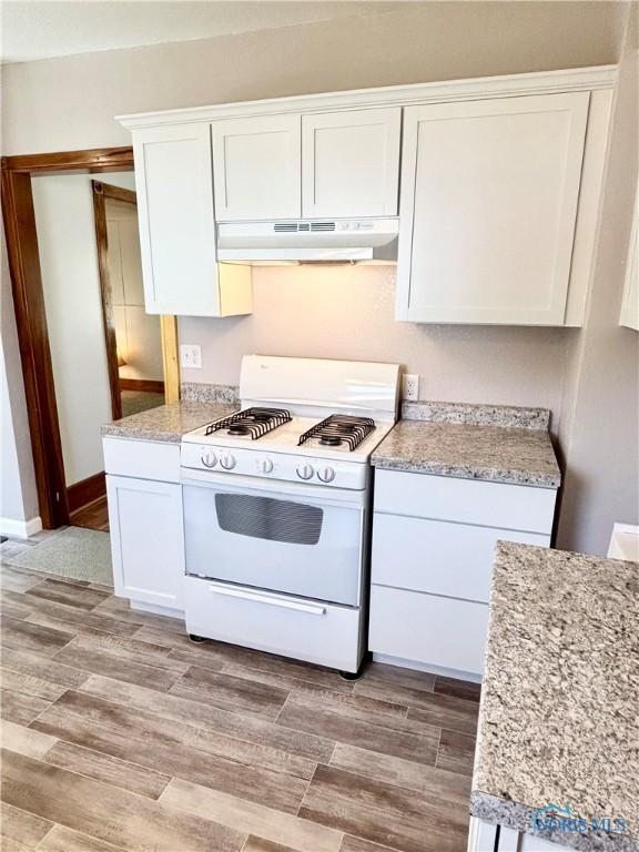 1522 Nevada St, Toledo, OH 43605 - kitchen with white gas range oven, under cabinet range hood, white cabinets, and baseboards