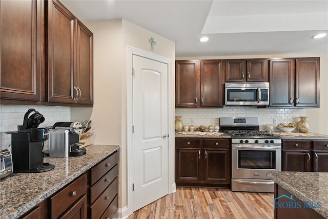 10 Hidden Village Ln, Holland, OH 43528 - kitchen with appliances with stainless steel finishes, light wood-type flooring, dark stone countertops, backsplash, and dark brown cabinets