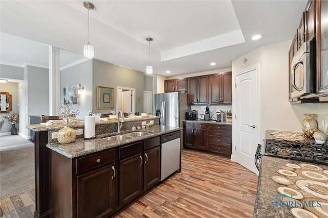 10 Hidden Village Ln, Holland, OH 43528 - kitchen featuring appliances with stainless steel finishes, pendant lighting, dark stone counters, a center island with sink, and dark brown cabinets