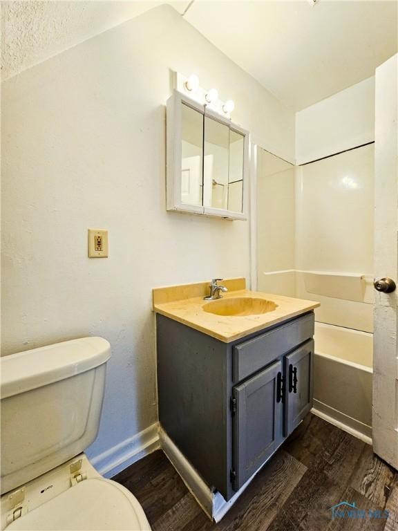 630 Highland Ave, Toledo, OH 43610 - bathroom with wood finished floors, toilet, vanity, a tub, and baseboards