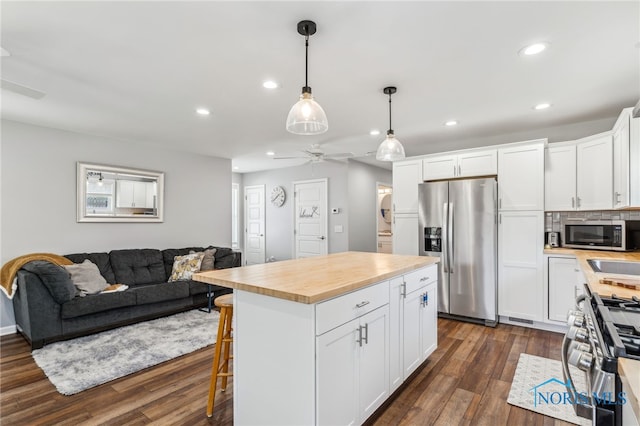 1313 Washington Ave, Findlay, OH 45840 - kitchen with stainless steel appliances, a ceiling fan, dark wood-type flooring, white cabinets, and a kitchen breakfast bar