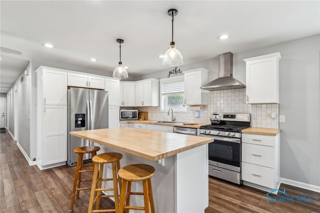1313 Washington Ave, Findlay, OH 45840 - kitchen featuring wood counters, wall chimney range hood, stainless steel appliances, a sink, and decorative backsplash