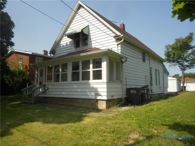 2815 Mulberry St, Toledo, OH 43608 - view of home's exterior featuring a yard, a chimney, and a sunroom