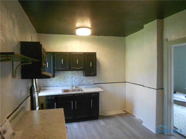 2815 Mulberry St, Toledo, OH 43608 - kitchen featuring a sink, light wood-style flooring, light countertops, and decorative backsplash