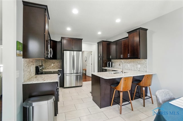 16187 Sugar Maple Ct, Findlay, OH 45840 - kitchen featuring stainless steel appliances, a sink, a peninsula, decorative backsplash, and dark brown cabinetry