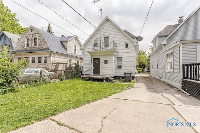 1129 Mason St, Toledo, OH 43605 - back of house featuring a balcony, a lawn, and concrete driveway